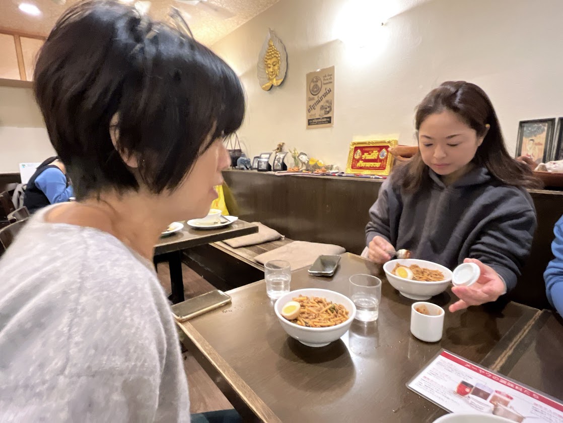 タイ料理屋の食事に調味料をかけている写真